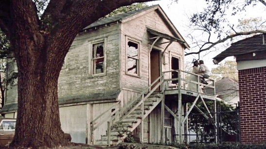picture of decaying garage apartment with couple kissing on porch